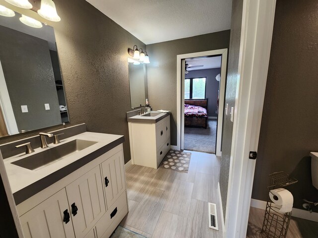 26575 US-71, Arago Twp, MN 56470 - ensuite bathroom featuring two vanities, a textured wall, baseboards, and wood finished floors