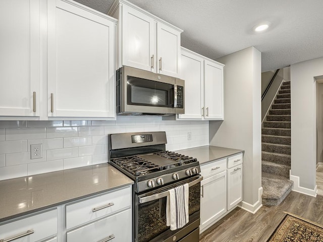1211 Lower 143rd St E, Rosemount, MN 55068 - kitchen featuring stainless steel appliances, dark wood finished floors, white cabinetry, decorative backsplash, and a textured ceiling