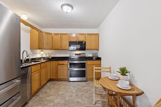 2517 Cobble Hill Ct Unit I, Woodbury, MN 55125 - kitchen featuring stainless steel appliances, a sink, dark countertops, a textured ceiling, and brown cabinetry