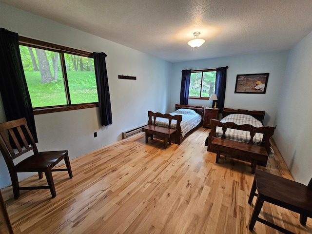 24429 Camp Lake Rd, Garrison, MN 56401 - bedroom featuring baseboard heating, light wood finished floors, and a textured ceiling