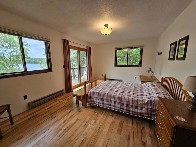 24429 Camp Lake Rd, Garrison, MN 56401 - bedroom with baseboard heating, hardwood / wood-style floors, access to exterior, and a textured ceiling
