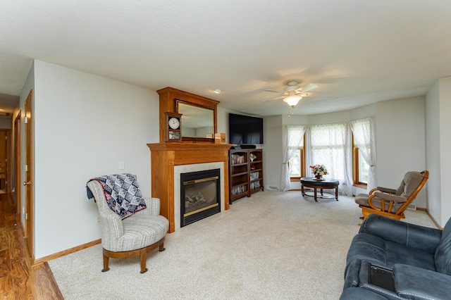1218 6th St NW, Dodge Center, MN 55927 - living area with a glass covered fireplace, a ceiling fan, baseboards, and carpet floors