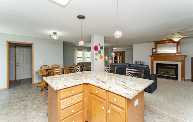 1218 6th St NW, Dodge Center, MN 55927 - kitchen featuring decorative light fixtures, open floor plan, a kitchen island, ceiling fan, and light stone countertops