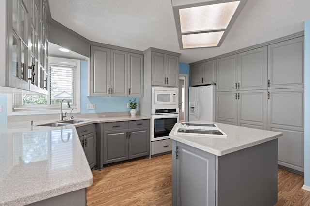 1902 Duck Pond Dr W, Saint Paul, MN 55118 - kitchen featuring gray cabinets, white appliances, a center island, light wood finished floors, and glass insert cabinets