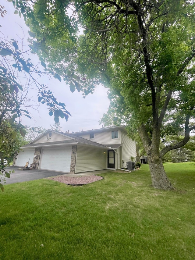 8405 97th St, Bloomington, MN 55438 - view of front of house with an attached garage, a front lawn, central air condition unit, asphalt driveway, and stone siding