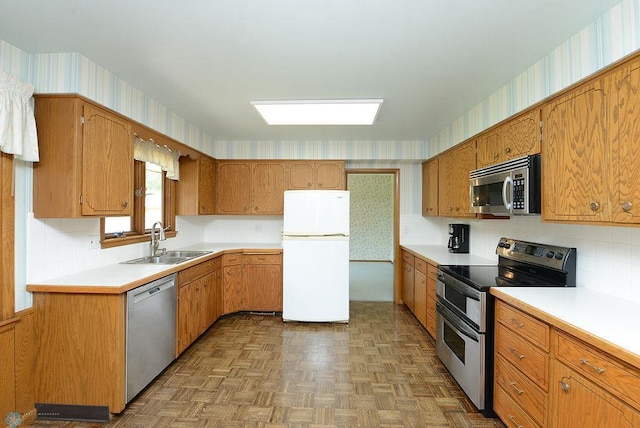 507 24th Ave S, Fargo, ND 58103 - kitchen featuring stainless steel appliances, wallpapered walls, light countertops, brown cabinetry, and backsplash