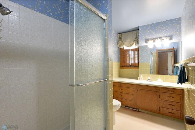 507 24th Ave S, Fargo, ND 58103 - bathroom featuring wallpapered walls, a shower stall, tile walls, vanity, and wainscoting