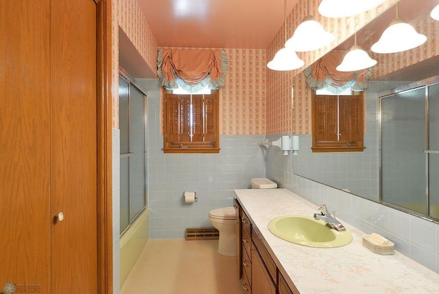507 24th Ave S, Fargo, ND 58103 - bathroom featuring wallpapered walls, vanity, tile walls, a wainscoted wall, and combined bath / shower with glass door