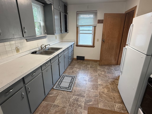19 1st Ave NE, Saint Joseph, MN 56374 - kitchen with freestanding refrigerator, a sink, backsplash, gray cabinets, and light countertops