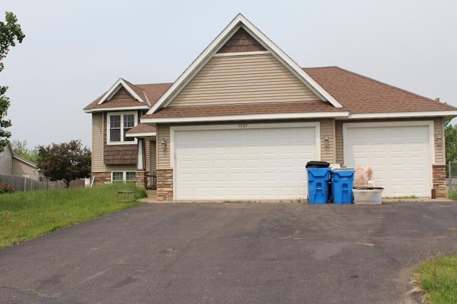 1027 Taft St S, Cambridge, MN 55008 - view of front of property featuring driveway, stone siding, an attached garage, and roof with shingles
