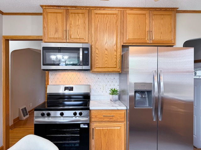 1759 Arlington Ave E, Saint Paul, MN 55106 - kitchen with stainless steel appliances, crown molding, backsplash, light countertops, and brown cabinets