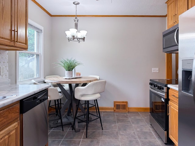1759 Arlington Ave E, Saint Paul, MN 55106 - kitchen with appliances with stainless steel finishes, crown molding, a chandelier, light countertops, and pendant lighting