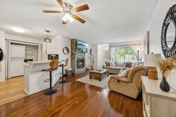 9955 Russell Ave N Unit 10, Brooklyn Park, MN 55444 - living room featuring estacked washer and dryer, light wood-style floors, a ceiling fan, a stone fireplace, and a textured ceiling