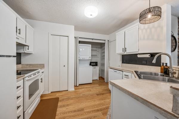 9955 Russell Ave N Unit 10, Brooklyn Park, MN 55444 - kitchen with stacked washing machine and dryer, a sink, white appliances, light wood finished floors, and white cabinetry