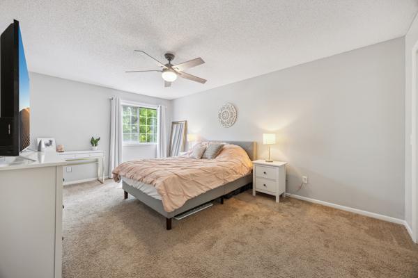 9955 Russell Ave N Unit 10, Brooklyn Park, MN 55444 - bedroom with light carpet, a textured ceiling, baseboards, and a ceiling fan