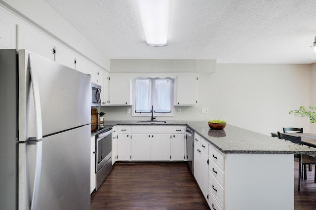 16503 Franklin Trl SE, Prior Lake, MN 55372 - kitchen with stainless steel appliances, a sink, a peninsula, dark countertops, and a textured ceiling