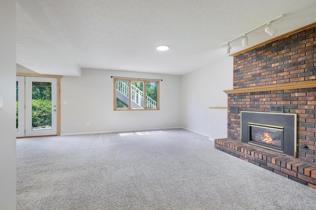 16503 Franklin Trl SE, Prior Lake, MN 55372 - unfurnished living room with track lighting, carpet flooring, baseboards, a brick fireplace, and a textured ceiling
