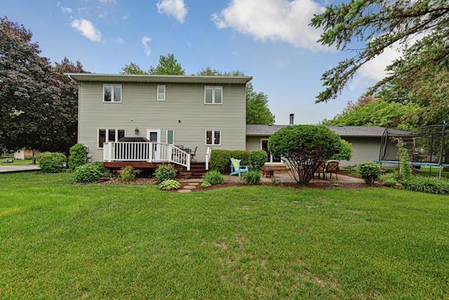1525 21st Ave NW, Faribault, MN 55021 - back of house featuring a trampoline, a deck, a yard, and a patio