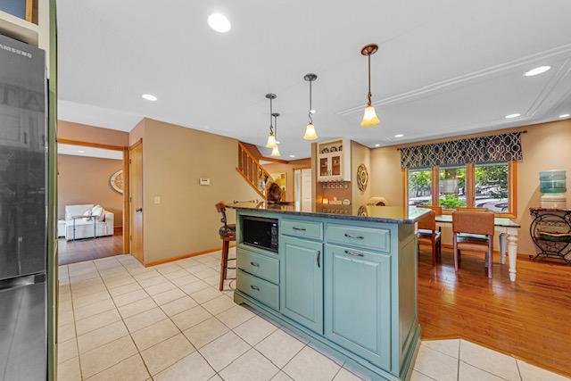 1525 21st Ave NW, Faribault, MN 55021 - kitchen with freestanding refrigerator, black microwave, light tile patterned floors, dark countertops, and recessed lighting
