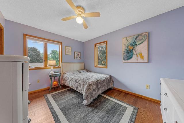 1525 21st Ave NW, Faribault, MN 55021 - bedroom with light wood finished floors, baseboards, ceiling fan, and a textured ceiling