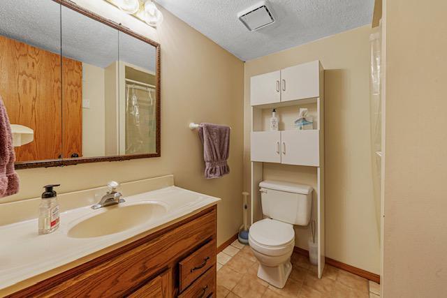 1525 21st Ave NW, Faribault, MN 55021 - bathroom with a textured ceiling, toilet, vanity, baseboards, and tile patterned flooring