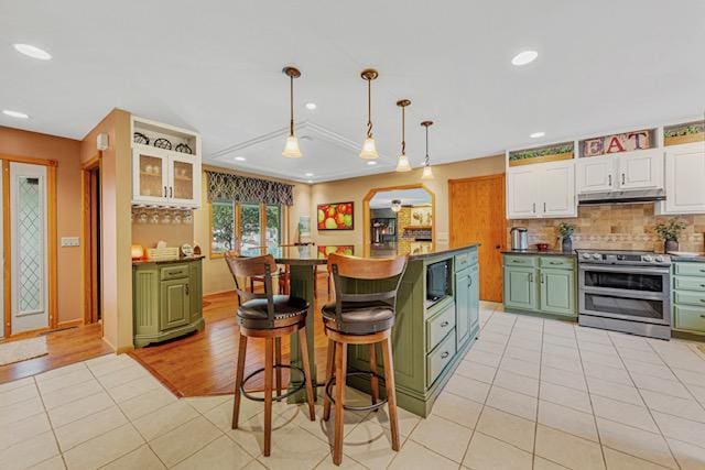 1525 21st Ave NW, Faribault, MN 55021 - kitchen featuring stainless steel electric range oven, under cabinet range hood, green cabinetry, white cabinets, and light tile patterned flooring