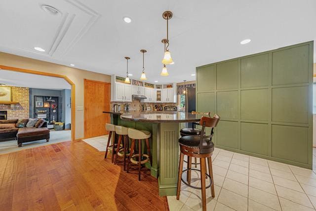 1525 21st Ave NW, Faribault, MN 55021 - kitchen featuring green cabinets, a kitchen bar, glass insert cabinets, dark countertops, and recessed lighting