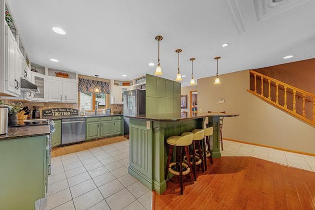 1525 21st Ave NW, Faribault, MN 55021 - kitchen featuring green cabinets, stainless steel appliances, under cabinet range hood, light tile patterned flooring, and dark countertops