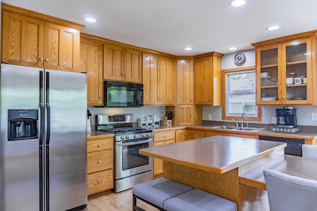 319 Casper Cir, Norwood Young America, MN 55368 - kitchen featuring stainless steel appliances, a sink, light wood-style floors, a breakfast bar, and glass insert cabinets