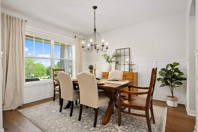 16632 Early Dawn Trl, Lakeville, MN 55044 - dining space with wood finished floors, a chandelier, wainscoting, a decorative wall, and arched walkways