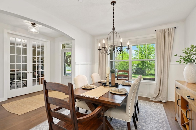 16632 Early Dawn Trl, Lakeville, MN 55044 - dining space featuring arched walkways, wainscoting, a chandelier, dark wood-style flooring, and french doors