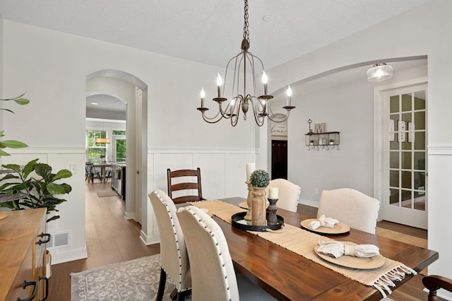16632 Early Dawn Trl, Lakeville, MN 55044 - dining area featuring arched walkways, dark wood-style floors, a wainscoted wall, a chandelier, and a decorative wall