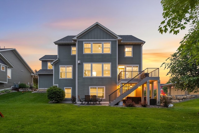 16632 Early Dawn Trl, Lakeville, MN 55044 - back of house at dusk featuring stairway, a lawn, board and batten siding, a patio area, and central AC