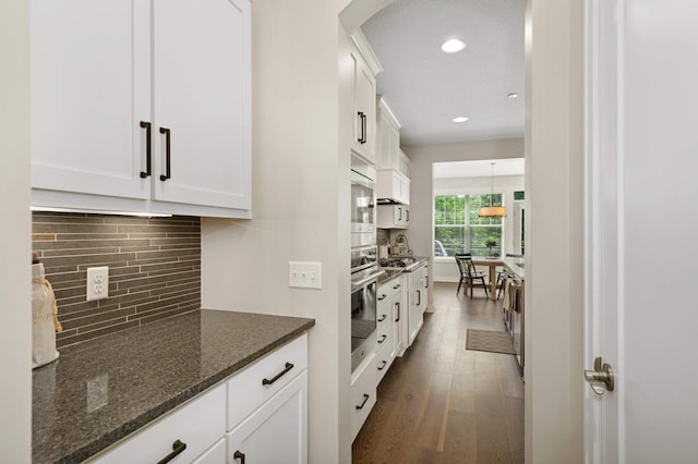 16632 Early Dawn Trl, Lakeville, MN 55044 - kitchen featuring white cabinetry, stainless steel appliances, arched walkways, dark wood finished floors, and backsplash