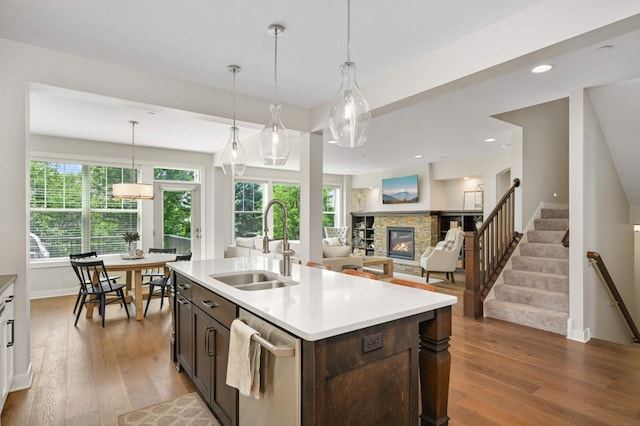 16632 Early Dawn Trl, Lakeville, MN 55044 - kitchen featuring dishwasher, a sink, a fireplace, dark brown cabinetry, and light countertops