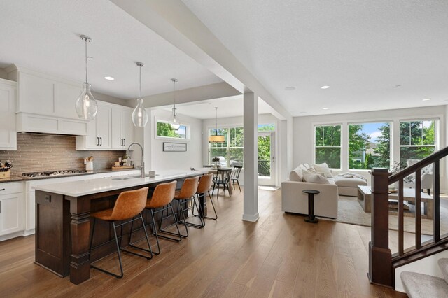 16632 Early Dawn Trl, Lakeville, MN 55044 - kitchen with a sink, a kitchen breakfast bar, tasteful backsplash, wood finished floors, and recessed lighting