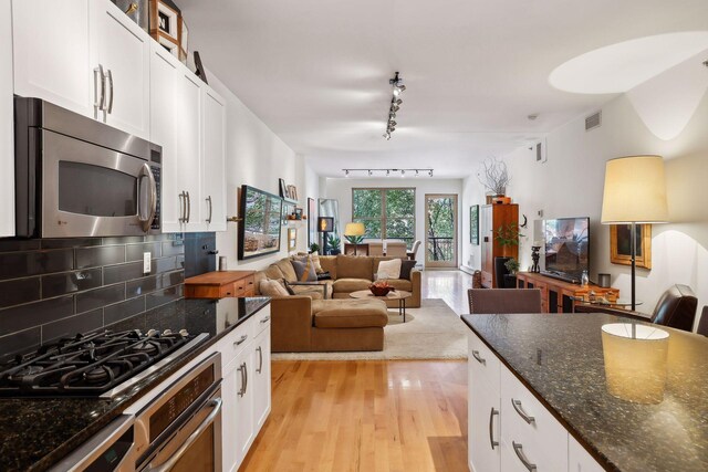 401 2nd St Unit 208, Minneapolis, MN 55401 - kitchen featuring stainless steel microwave, wall oven, black gas cooktop, rail lighting, and light wood-type flooring