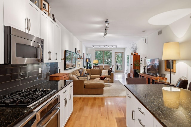 401 2nd St Unit 208, Minneapolis, MN 55401 - kitchen featuring appliances with stainless steel finishes, track lighting, light wood-style floors, decorative backsplash, and white cabinets