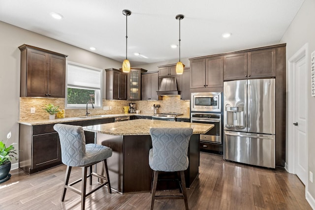 14143 Ailesbury Ave, Rosemount, MN 55068 - kitchen with appliances with stainless steel finishes, custom exhaust hood, dark brown cabinets, a breakfast bar, and recessed lighting