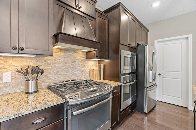14143 Ailesbury Ave, Rosemount, MN 55068 - kitchen with appliances with stainless steel finishes, range hood, dark brown cabinets, dark wood finished floors, and a textured ceiling