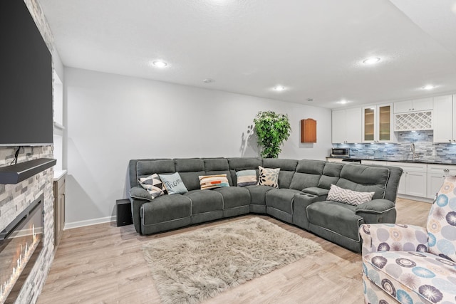 14143 Ailesbury Ave, Rosemount, MN 55068 - living room featuring light wood-style flooring, a stone fireplace, wet bar, and recessed lighting