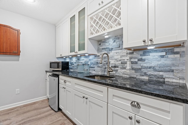 14143 Ailesbury Ave, Rosemount, MN 55068 - kitchen featuring stainless steel microwave, dark stone countertops, white cabinetry, tasteful backsplash, and glass insert cabinets