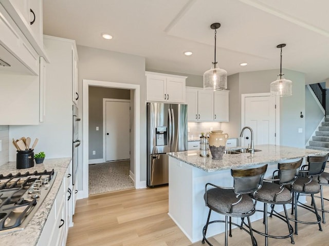 68 143rd Ave NW, Andover, MN 55304 - kitchen with appliances with stainless steel finishes, a sink, white cabinets, a breakfast bar area, and light stone counters