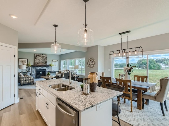 68 143rd Ave NW, Andover, MN 55304 - kitchen with stainless steel dishwasher, a sink, white cabinetry, a stone fireplace, and pendant lighting