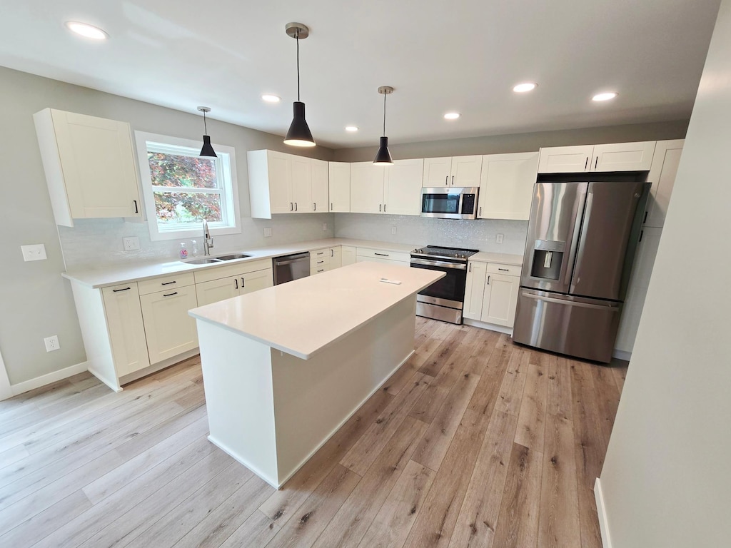2710 Garden Ln, Mound, MN 55364 - kitchen featuring appliances with stainless steel finishes, a sink, light wood-style floors, tasteful backsplash, and white cabinetry