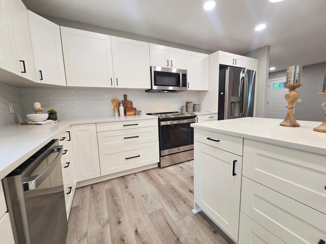 2710 Garden Ln, Mound, MN 55364 - kitchen with appliances with stainless steel finishes, light wood-style flooring, light countertops, tasteful backsplash, and white cabinetry