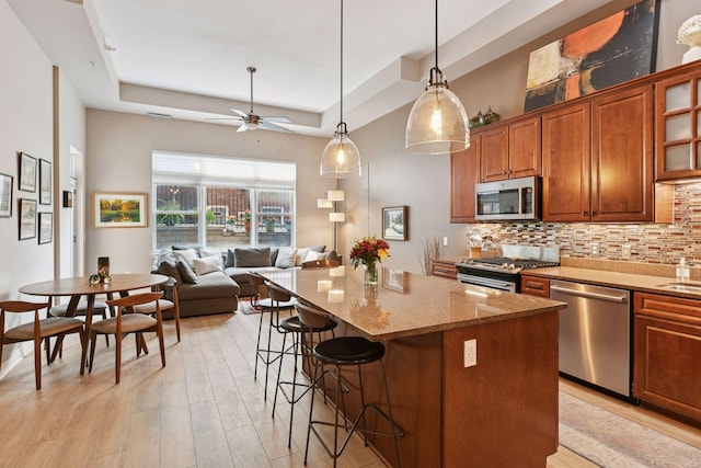 301 Clifton Ave Unit 1K, Minneapolis, MN 55403 - kitchen featuring stainless steel appliances, a tray ceiling, a kitchen bar, light stone counters, and a kitchen island