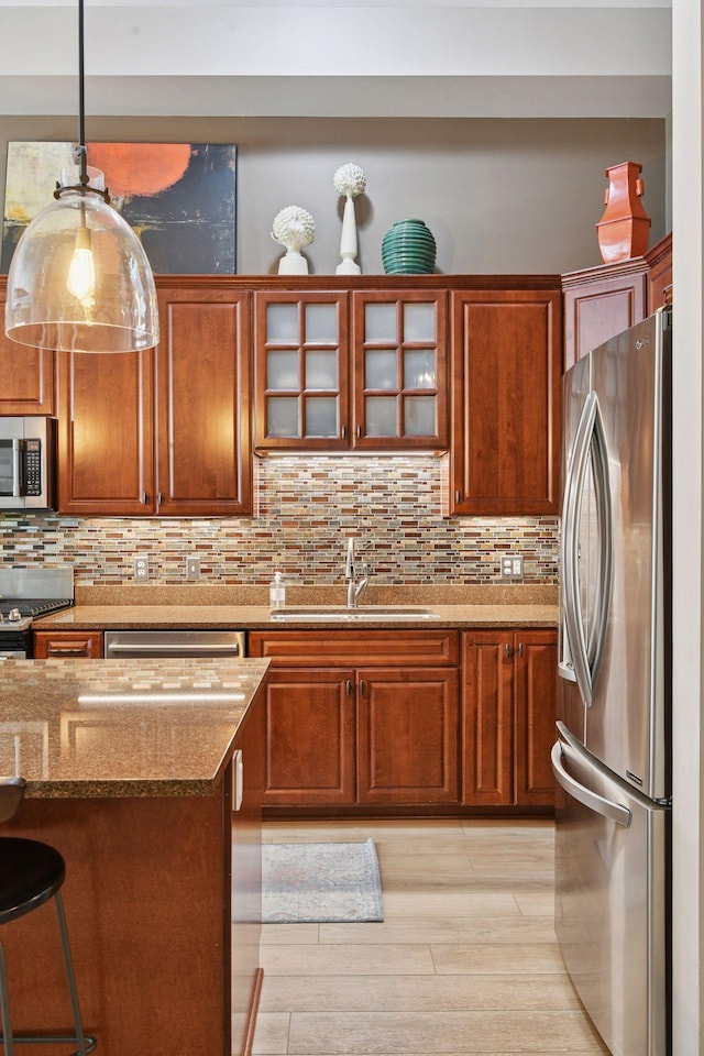 301 Clifton Ave Unit 1K, Minneapolis, MN 55403 - kitchen with appliances with stainless steel finishes, a sink, decorative backsplash, glass insert cabinets, and light stone countertops