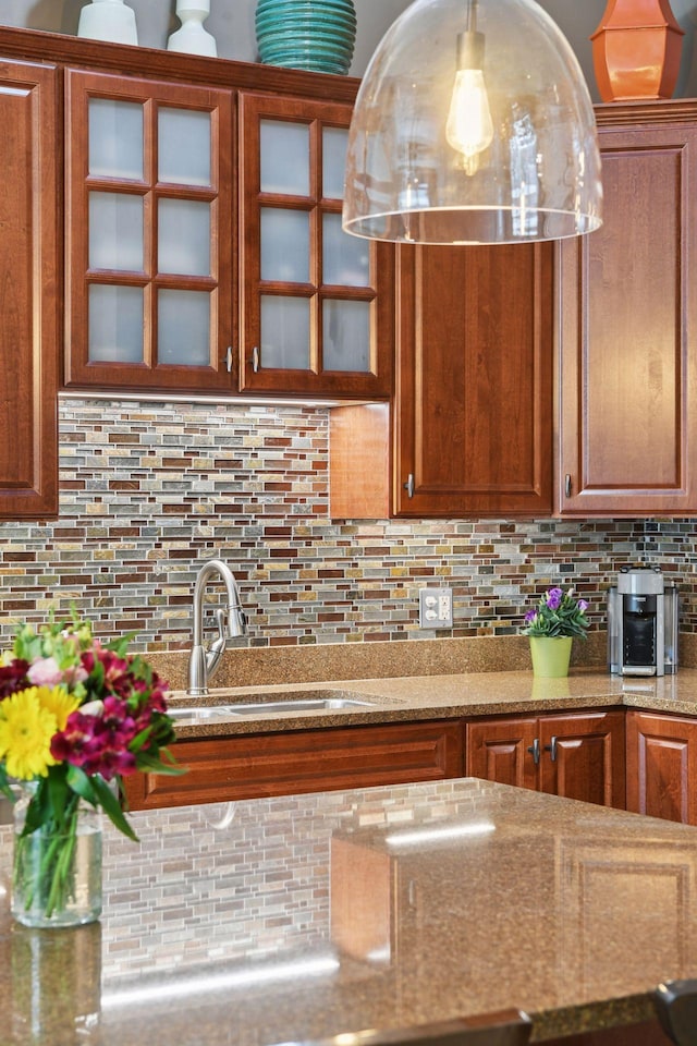 301 Clifton Ave Unit 1K, Minneapolis, MN 55403 - kitchen featuring a sink, tasteful backsplash, glass insert cabinets, and brown cabinets