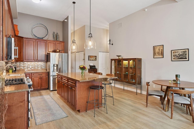 301 Clifton Ave Unit 1K, Minneapolis, MN 55403 - kitchen with appliances with stainless steel finishes, high vaulted ceiling, a sink, a breakfast bar area, and tasteful backsplash